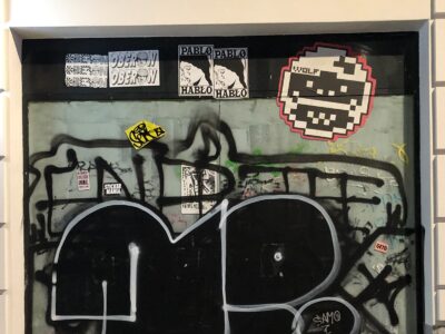 A mix of stickers and graffiti on a wall