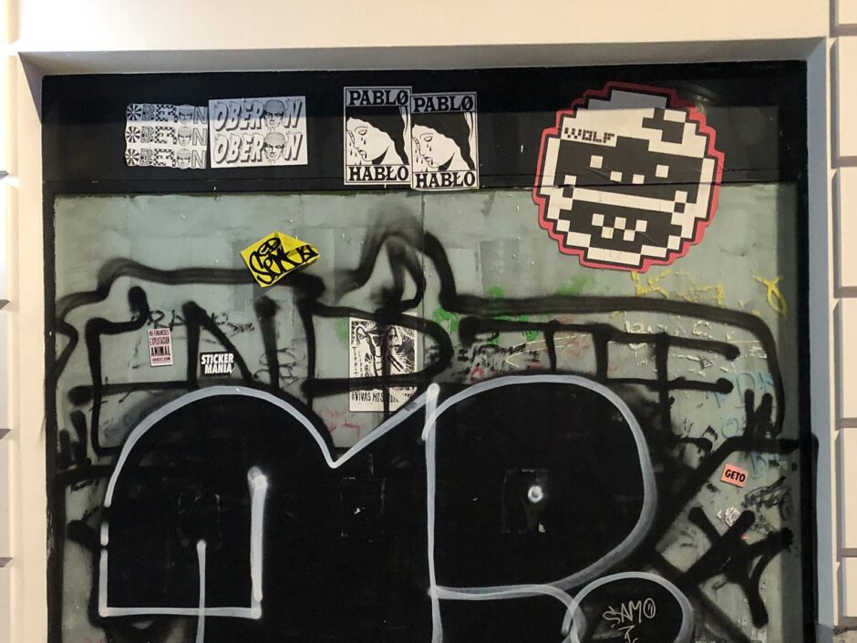 A mix of stickers and graffiti on a wall